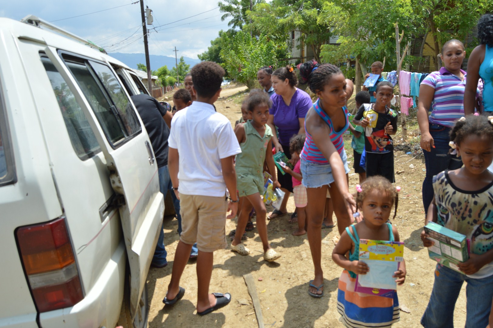 Children and their guardians outside the car receiving toys from our staff