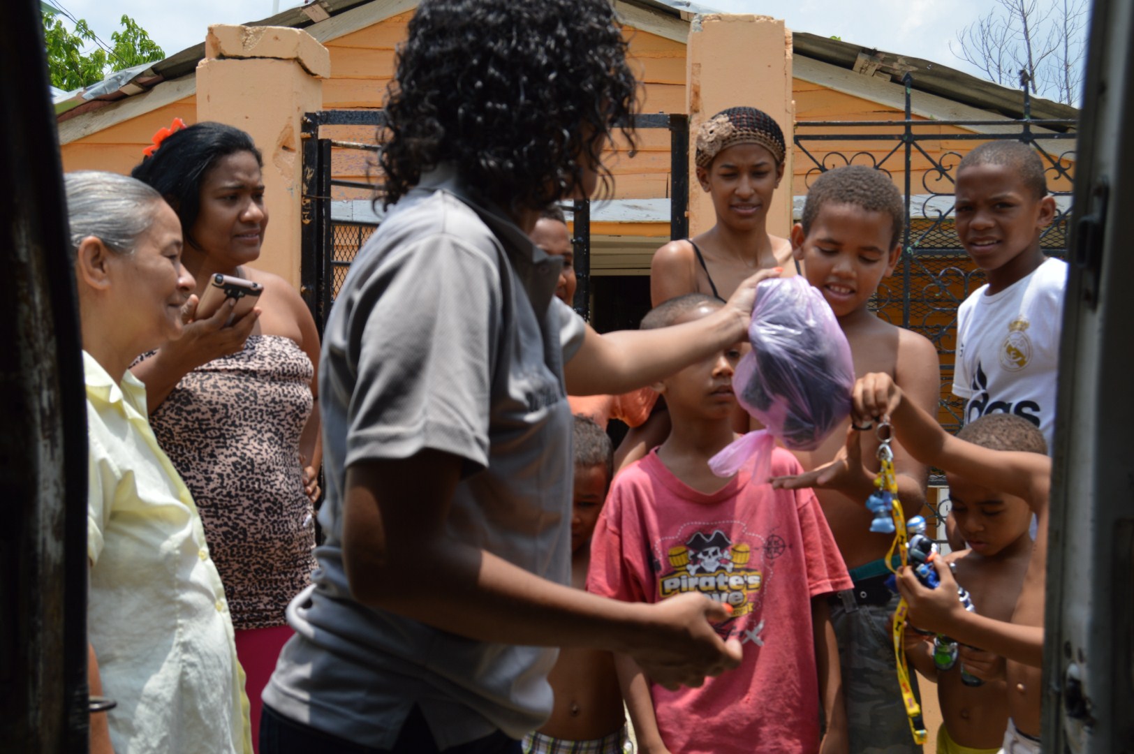 Staff giving out a plastic bag to a child; women and other children watching