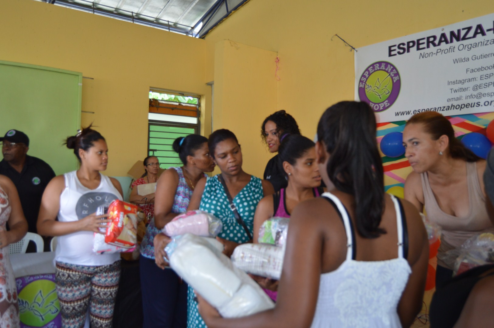 Mothers receiving packs of diapers and clothes, different angle