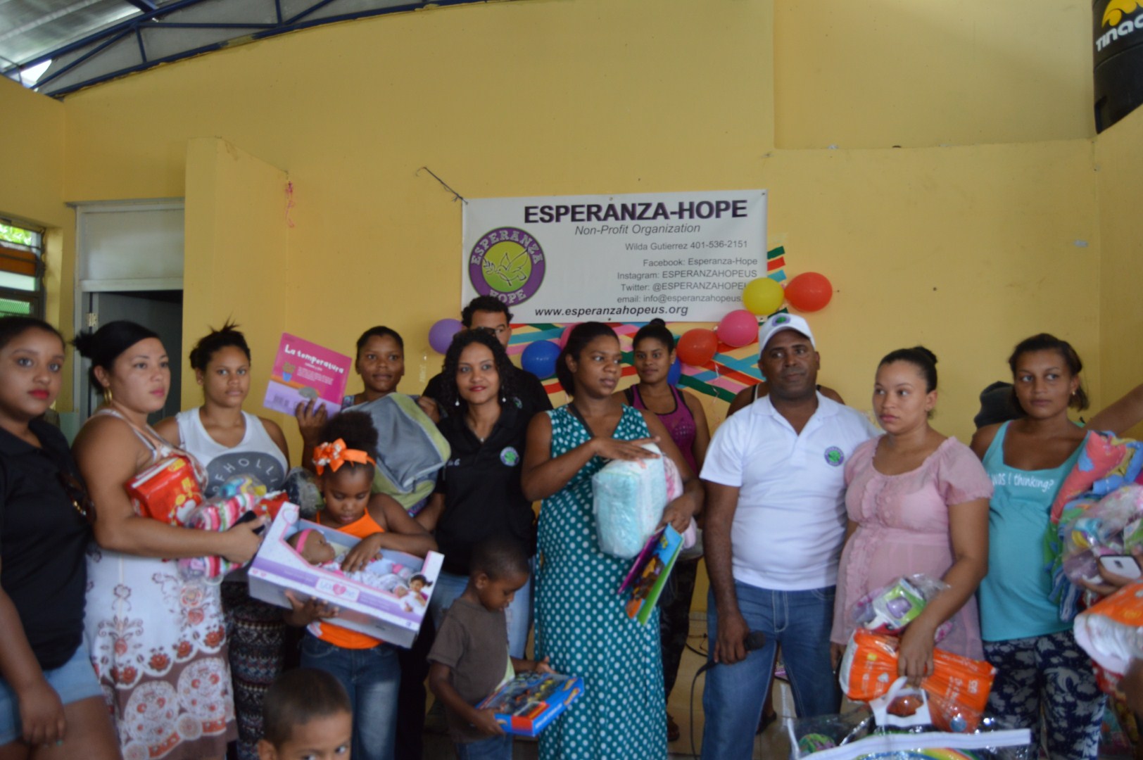 The mothers and some of their children holding toys, diapers, and clothes, another angle