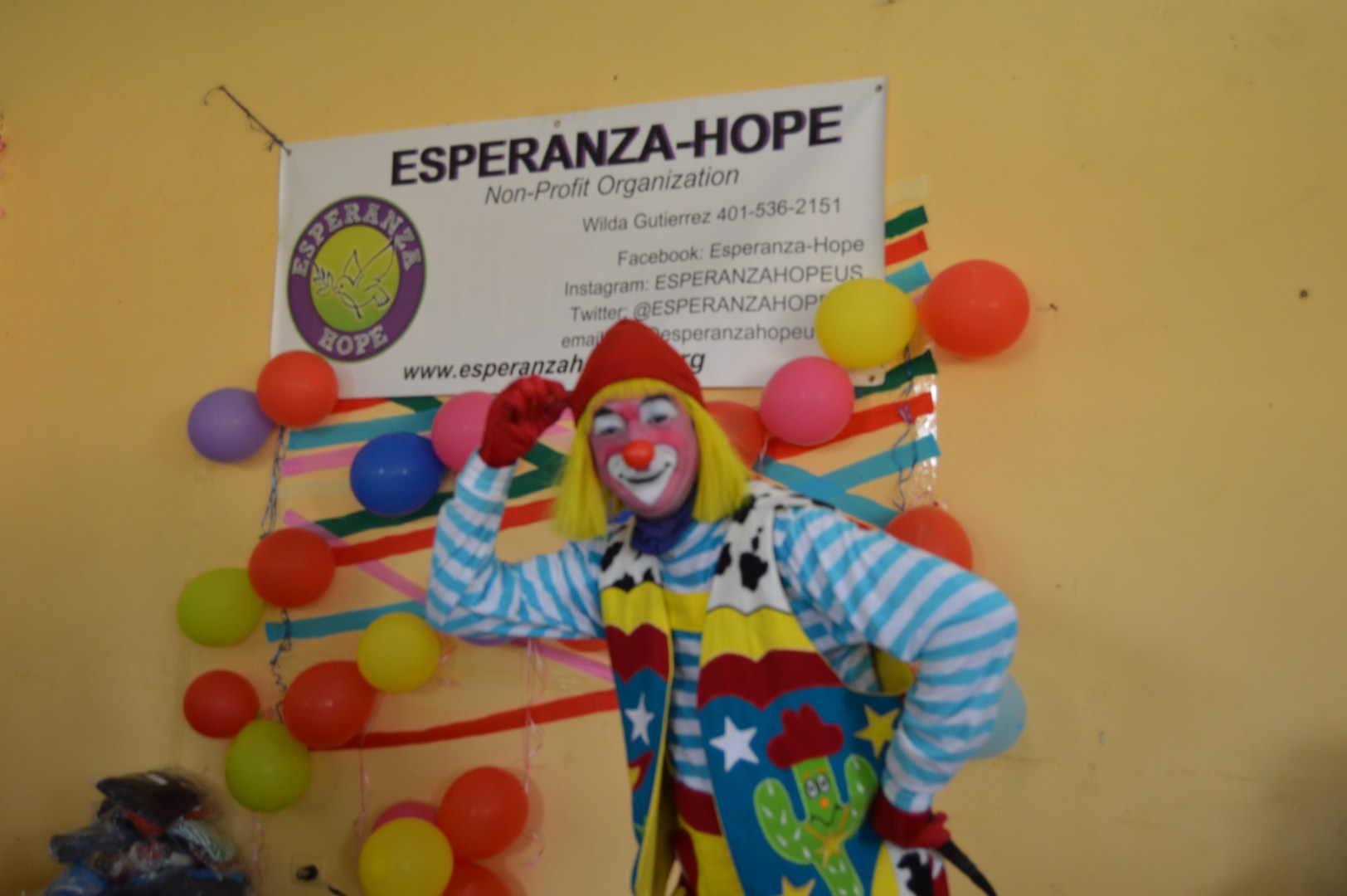 A clown posing in front of Esperanza-Hope’s tarpaulin