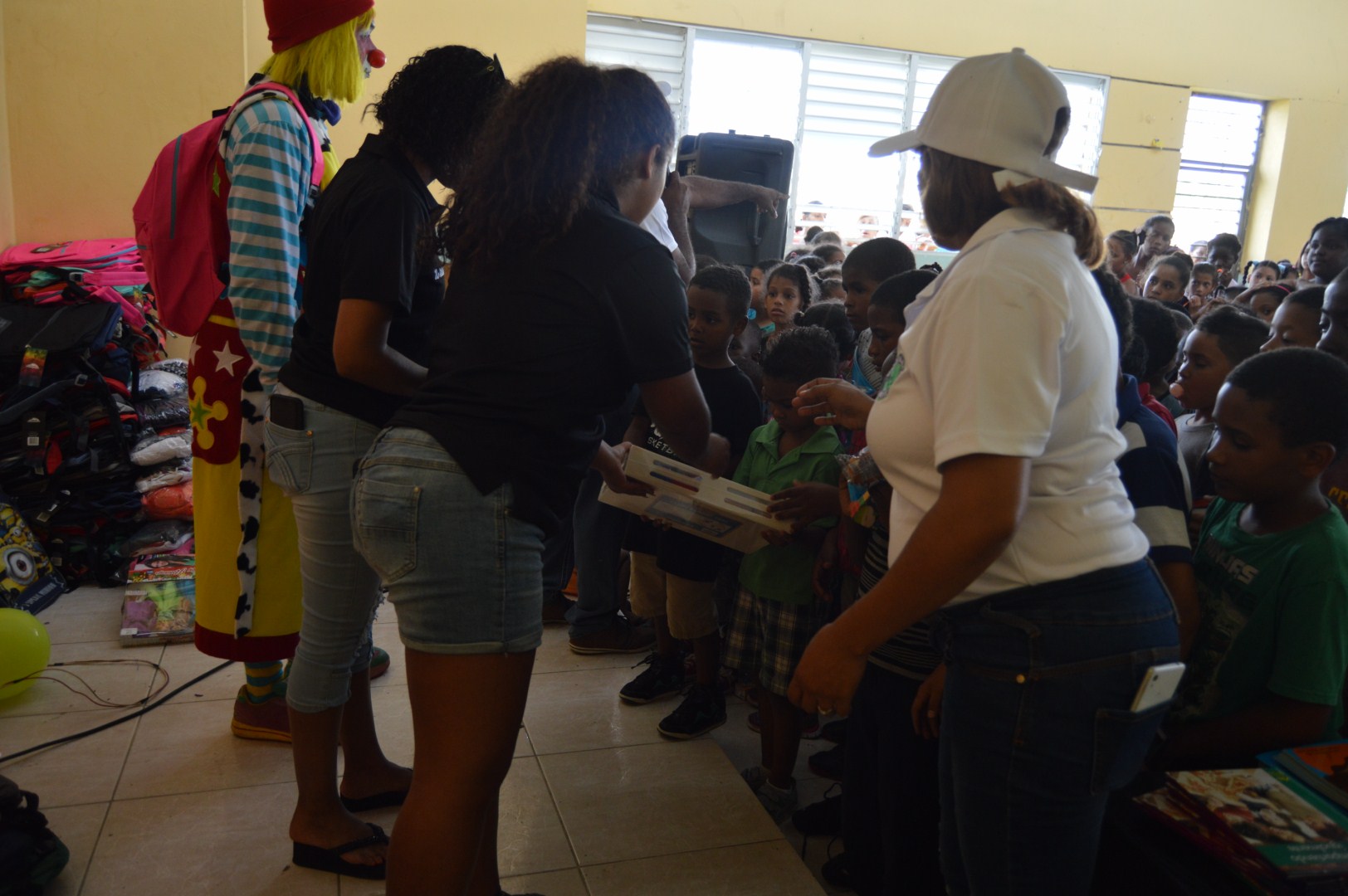 Two staff giving a child a toy, the clown beside them