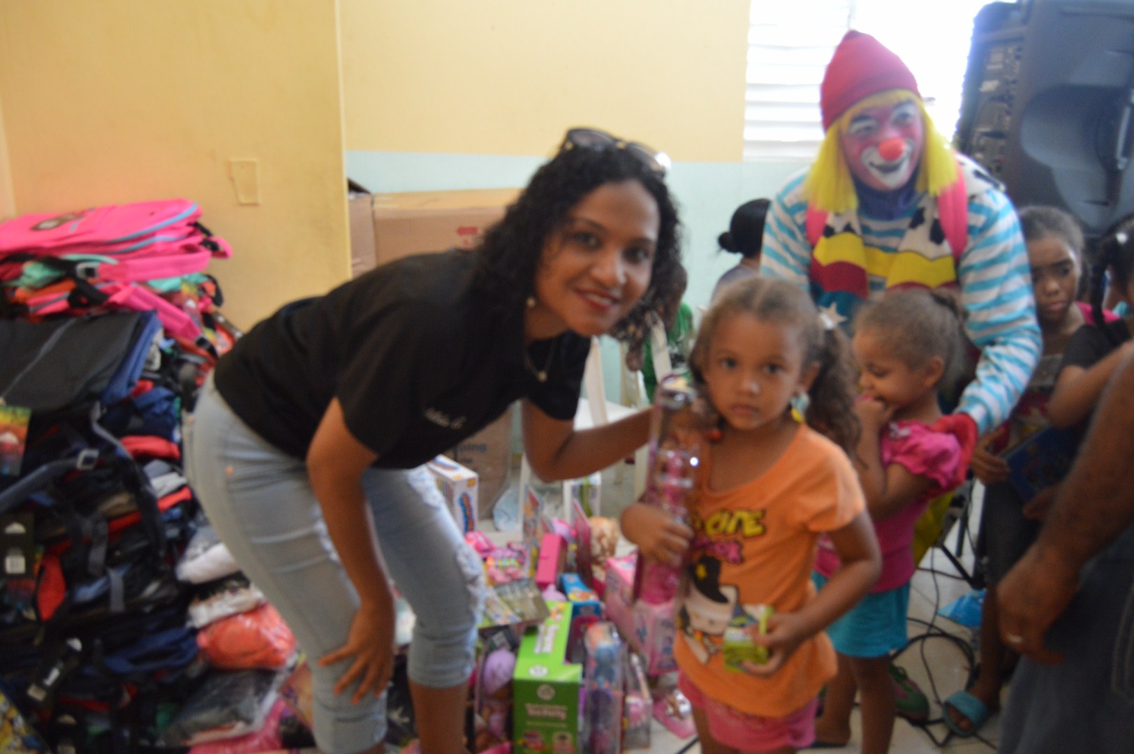 A staff and a girl holding a Barbie, the clown and another child behind them