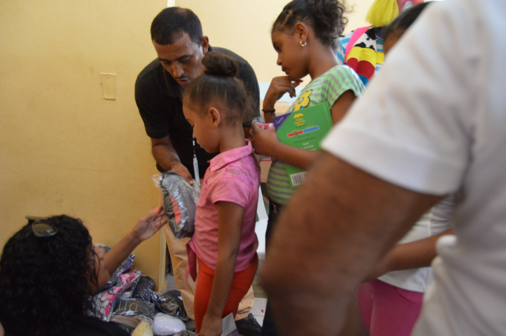 A child receiving a pack of clothes from two staff