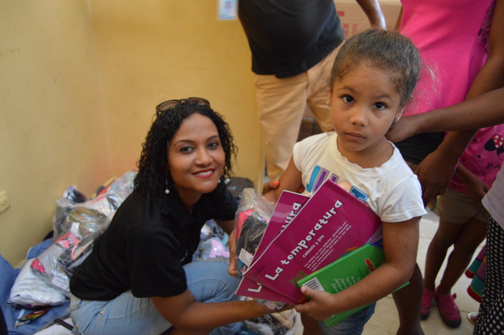 Our staff and a young girl holding books and a pack of clothes