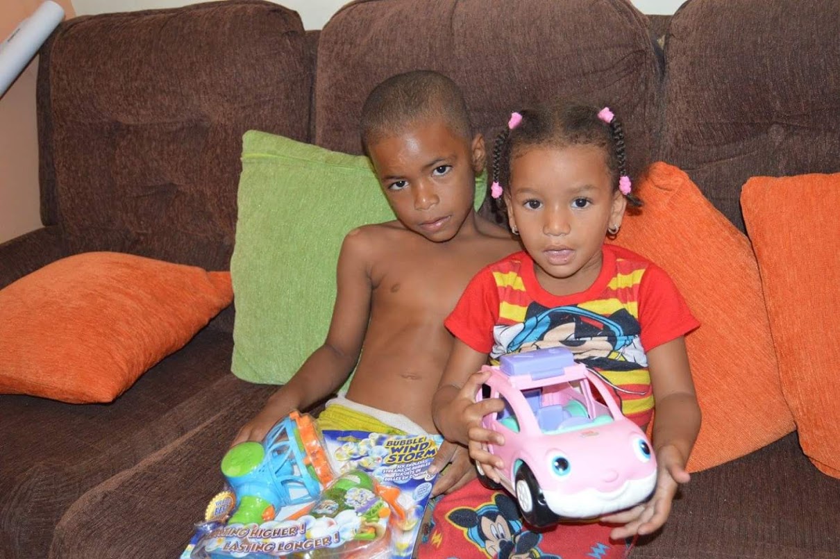A young boy and a girl sitting on a couch and holding toys