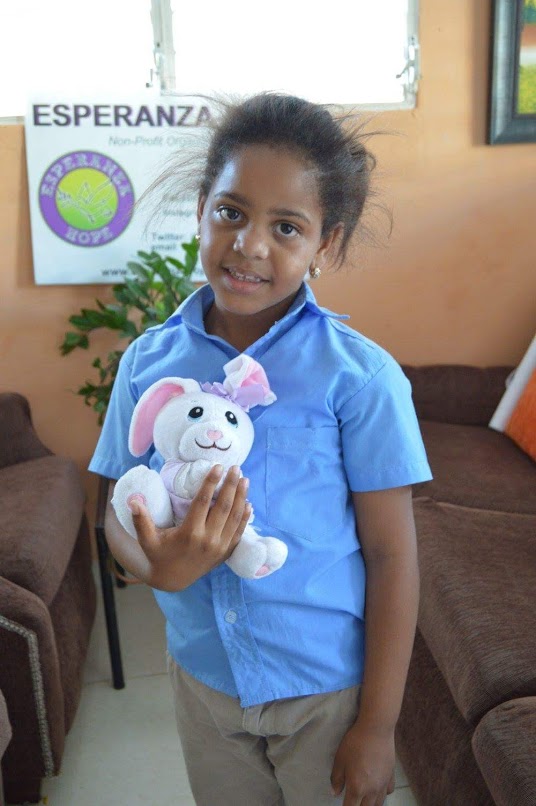 A girl smiling and holding a bunny stuffed toy