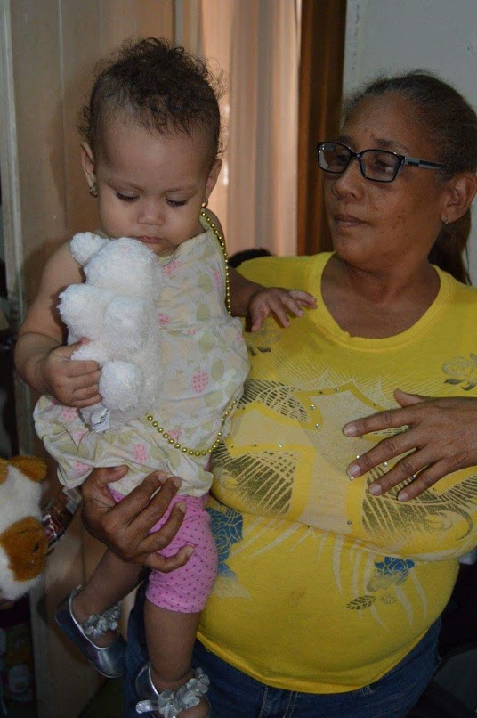 A woman carrying a little girl who is holding a white stuffed toy