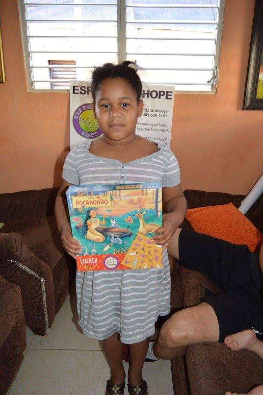 A girl in a dress holding a Pocahontas toy box