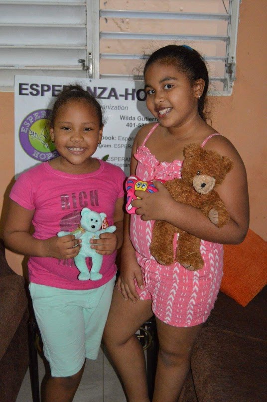 Two girls in pink tops, both holding teddy bears