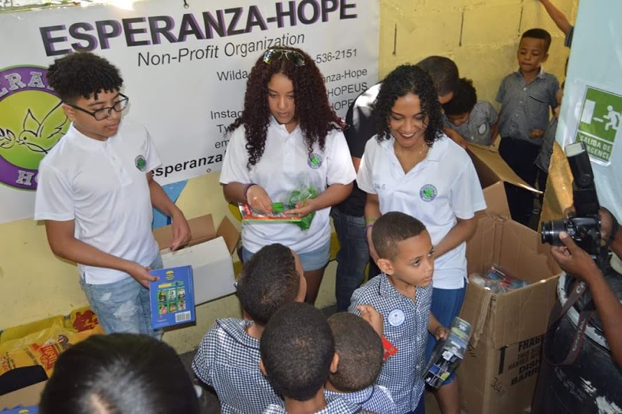 Three staff giving out green wristbands and books to children, 2