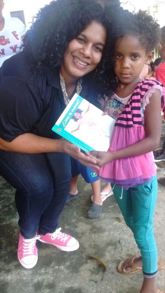 Our staff giving a book to a little girl wearing a pink top