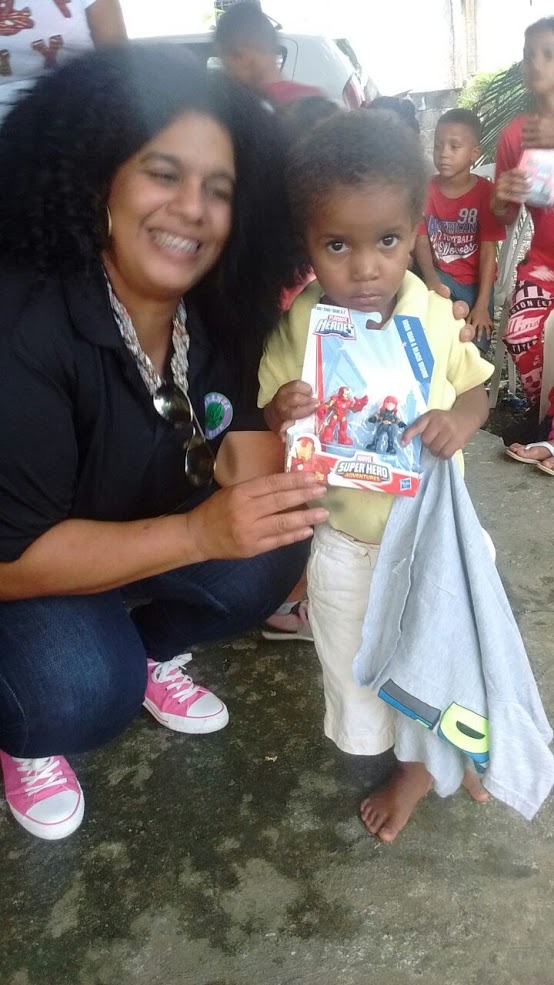 A woman smiling and a young child holding a shirt and a toy