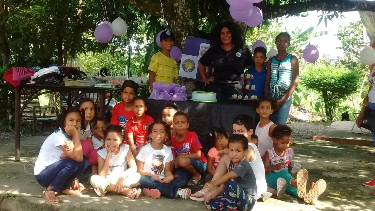 Our staff and children posing at the table with cake under a tree
