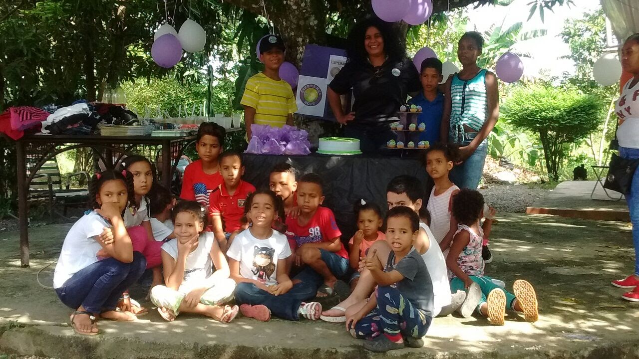 Our staff and children posing at the table with cake under a tree (version 2)