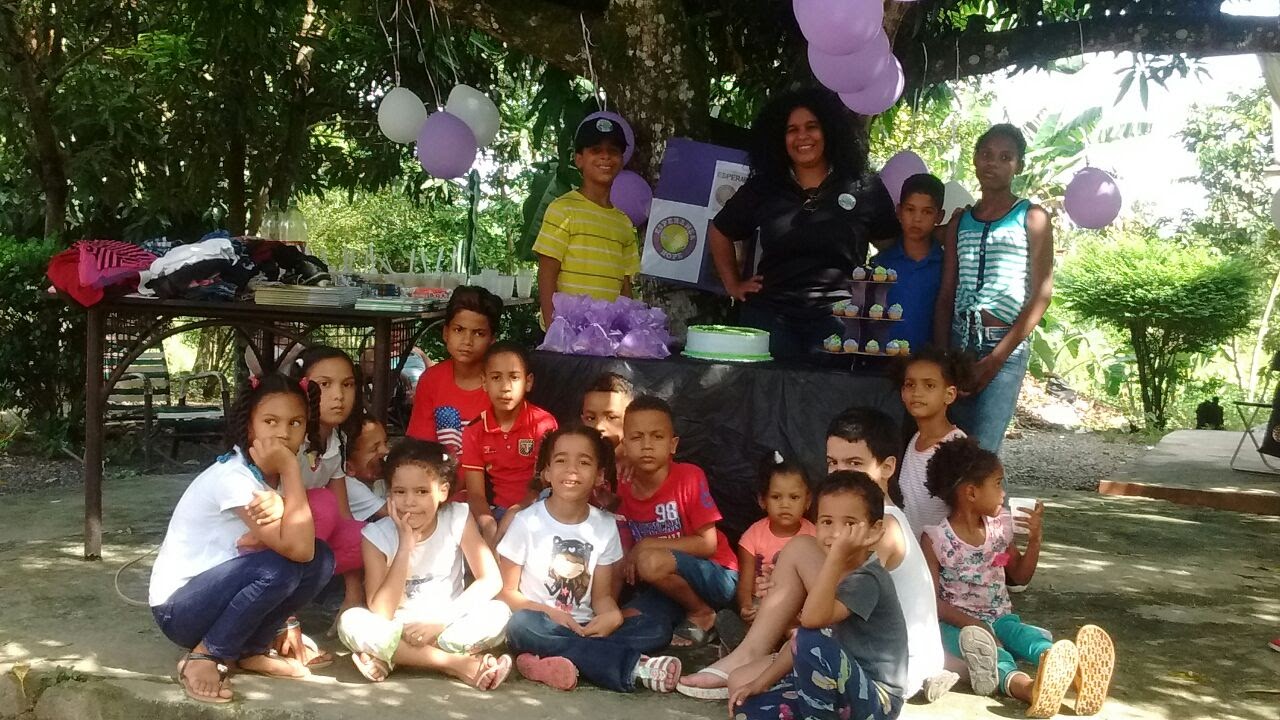 Our staff and children posing at the table with cake under a tree (version 3)