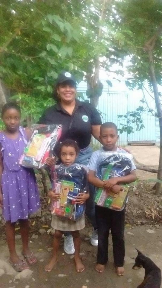 Three children receiving bags and school supplies