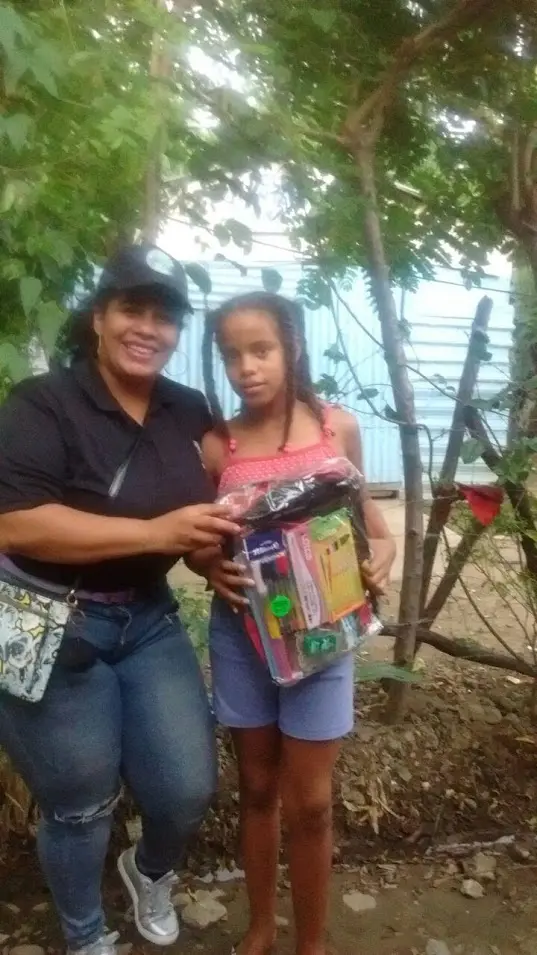 A girl with braids receiving a bag and school supplies