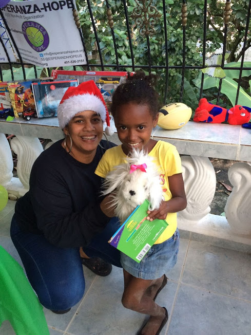 A female staff with a Santa hat and a girl holding a puppy stuffed toy (2)