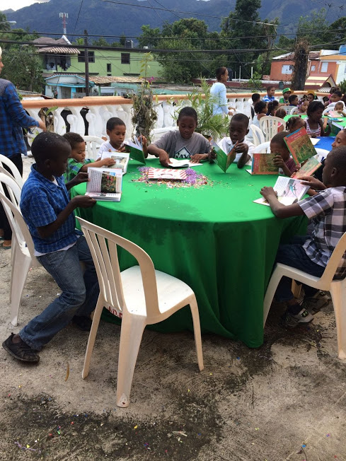 Children sitting at a green table and reading their books