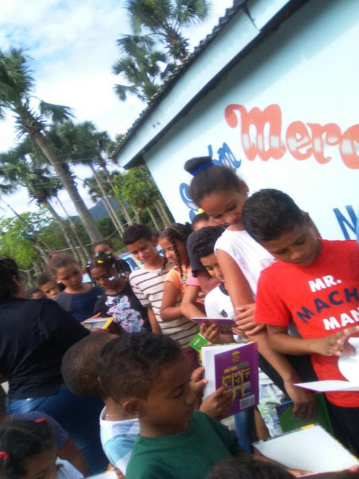A female staff giving out books to children at the back of the line