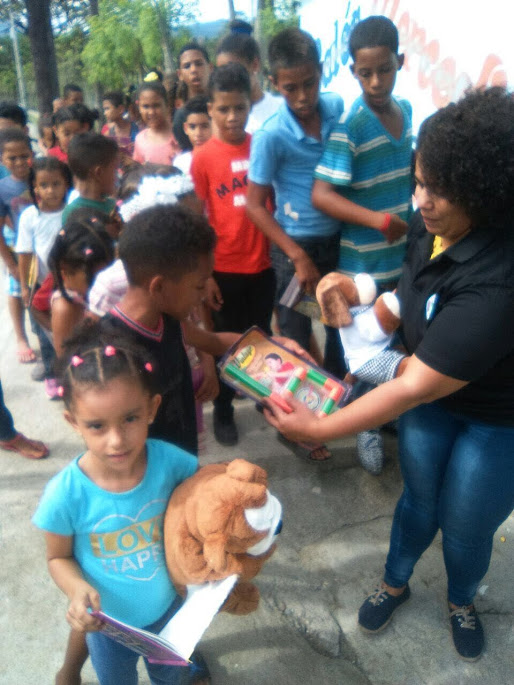 A female staff giving out toys to the children in front of the line