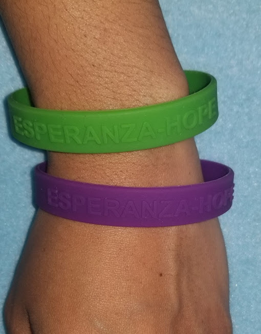 A hand with a green and purple wristband