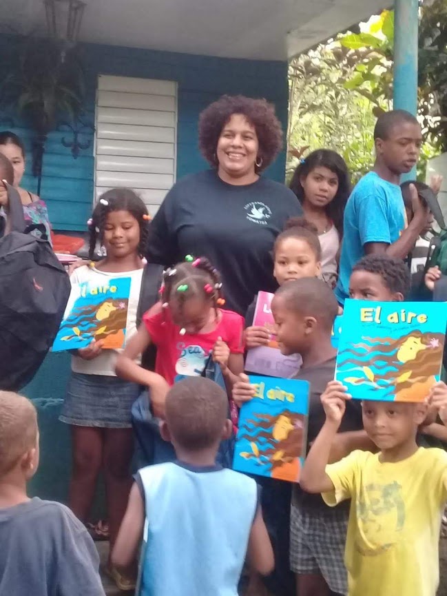 A woman and the children smiling, raising their books