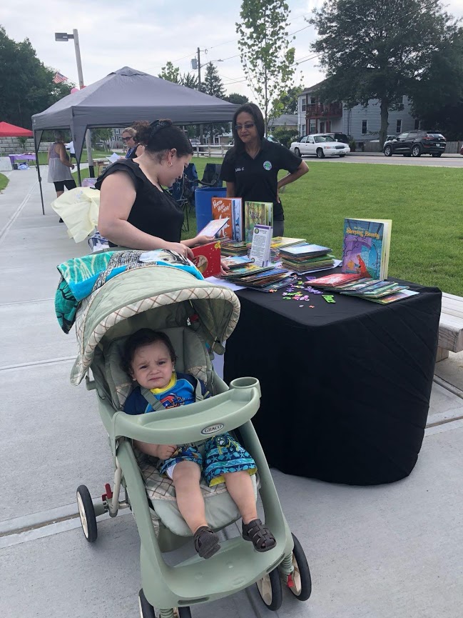 A woman with her baby in a stroller picks out books from our table