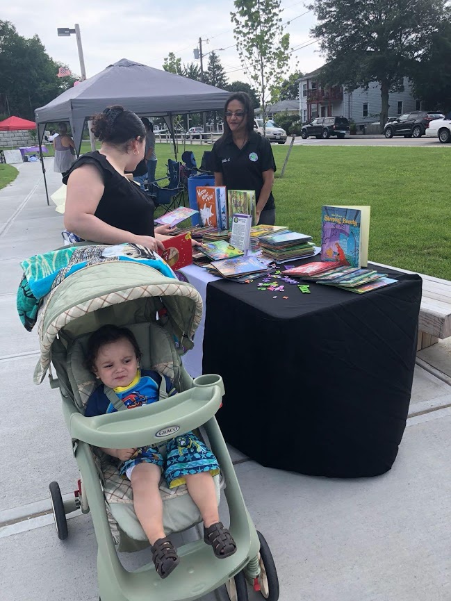 A woman with her baby in a stroller looks at more books from our table
