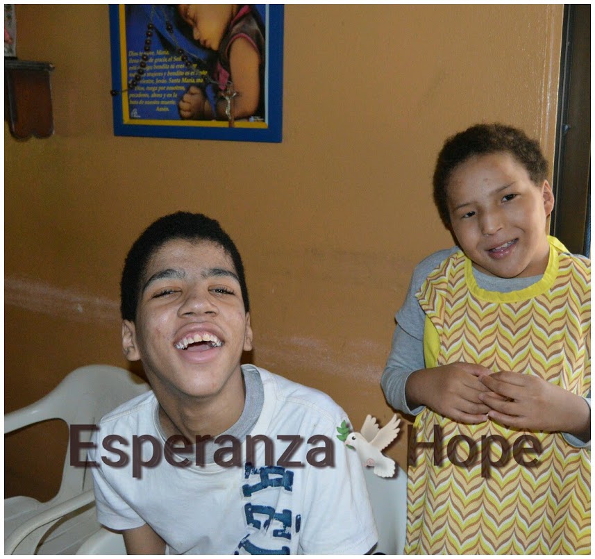A boy in white shirt sitting and a girl wearing a yellow apron standing. Text: Esperanza-Hope