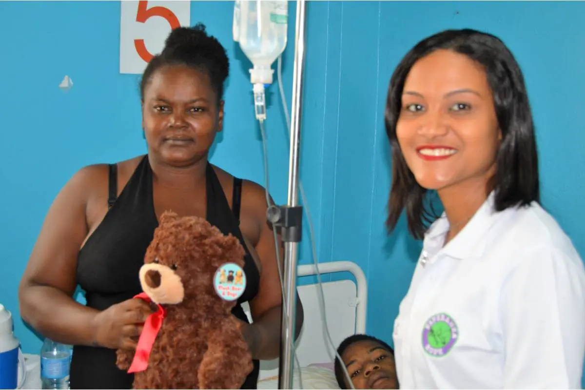 Our staff, a woman holding a teddy bear, and a child in a hospital bed