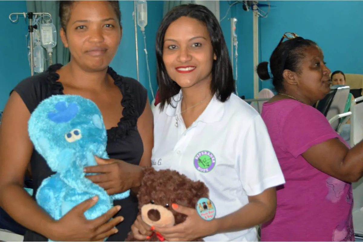 A female staff and a woman, both holding teddy bears