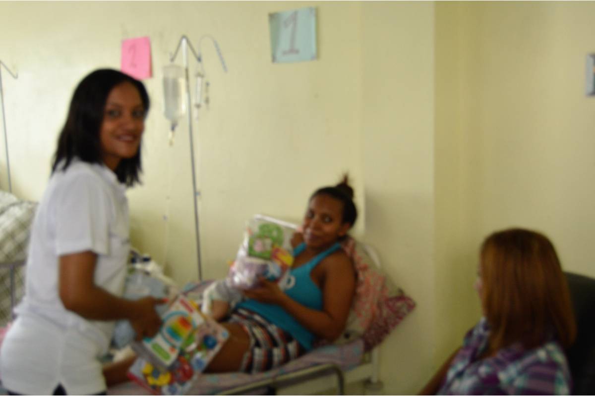 Our staff giving clothes and toys to a woman carrying a baby in a hospital bed