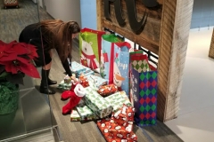 A girl placing a gift on a pile of gifts on the floor