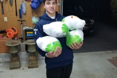 A boy holding four bags of turkey