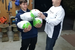 A boy holding four bags of turkey and a man getting one of the bags