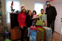 Two of our staff, a mother carrying her daughter, and her son posing with the presents