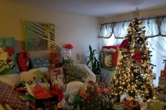 A living room with a Christmas tree that is full of gifts