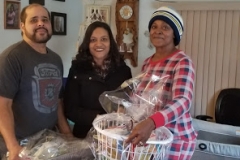 A man and two women, with one of them holding a basket of groceries