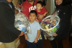Cropped photo of a three adults and two boys, with two adults holding a basket and bag of turkey