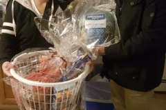 Cropped photo of two people holding a bag of turkey and a basket of groceries