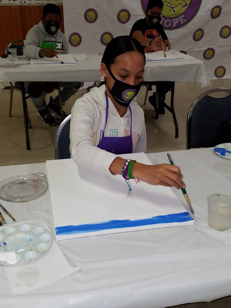 A woman in jacket and apron painting the canvas blue
