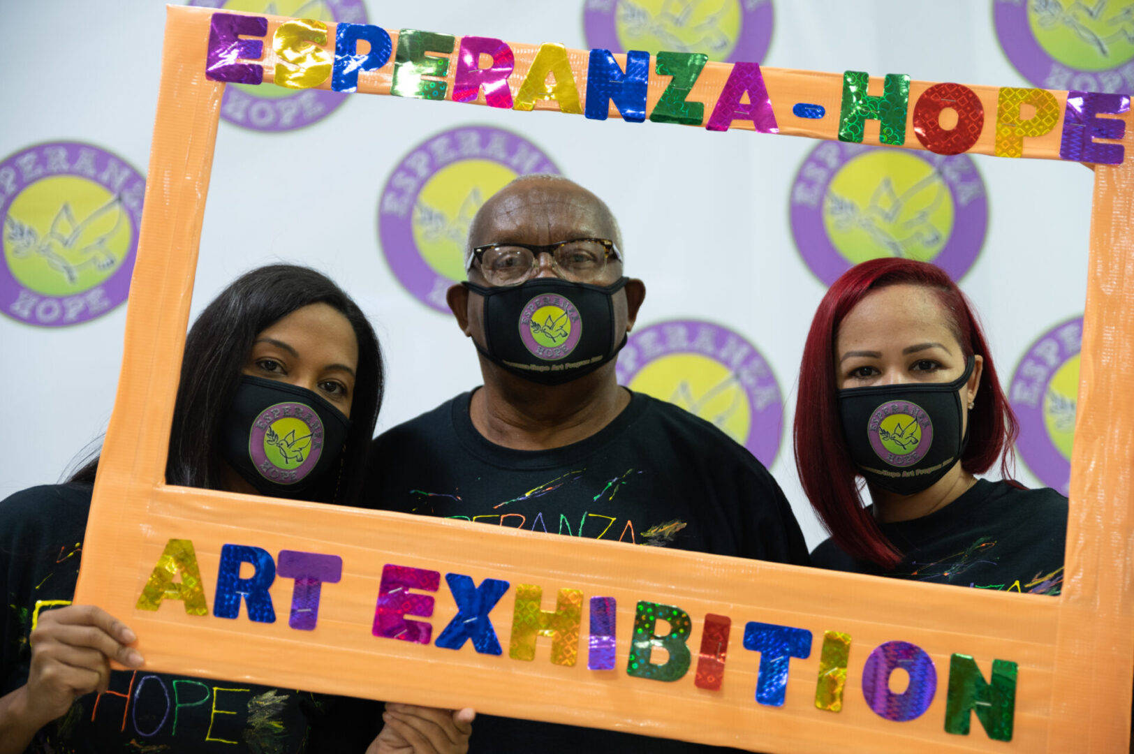 Two female staff and a male staff posing with the Esperanza-Hope’s Art Exhibition frame