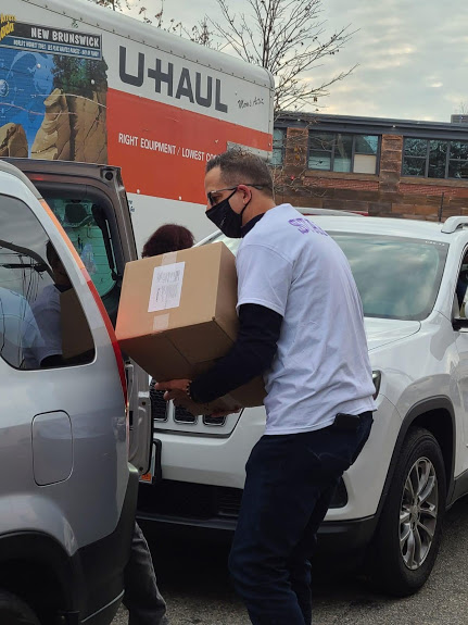 A man carrying a box and opening a car