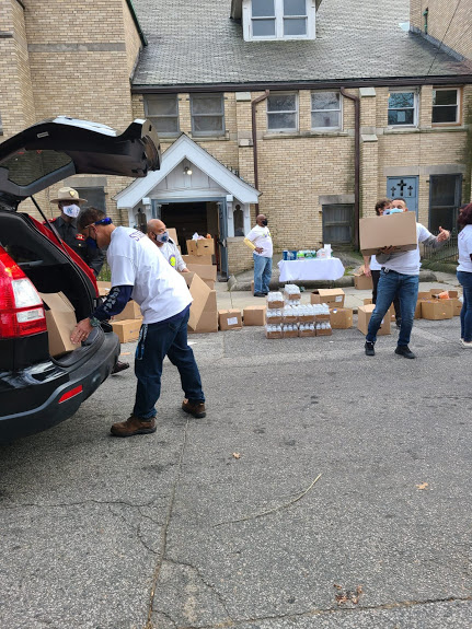 Our staff putting a box of food in a black car’s trunk