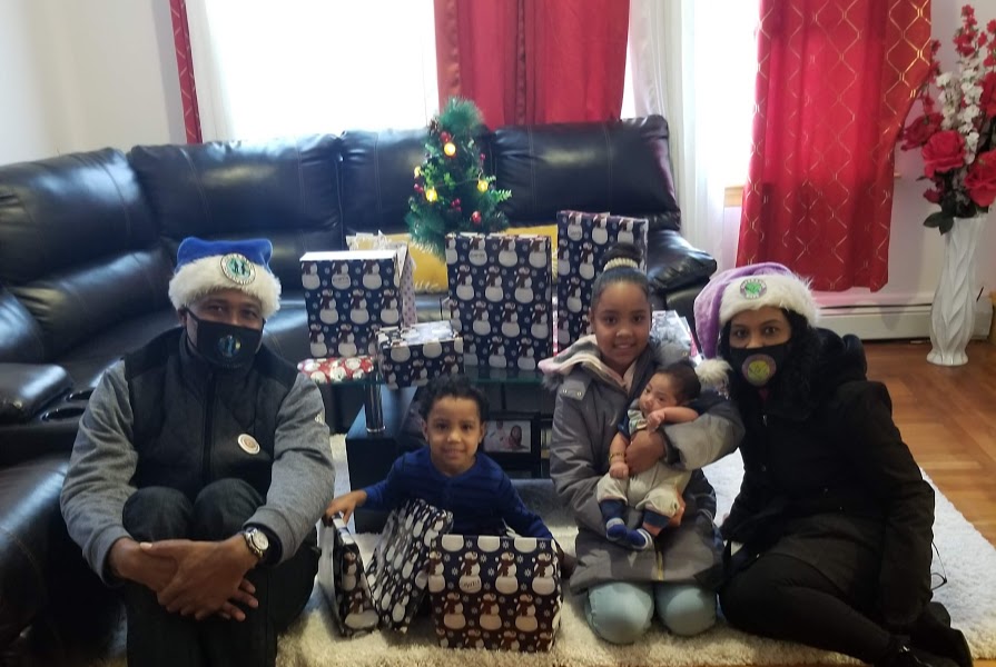 A family of five sitting on the floor of their living room with gifts
