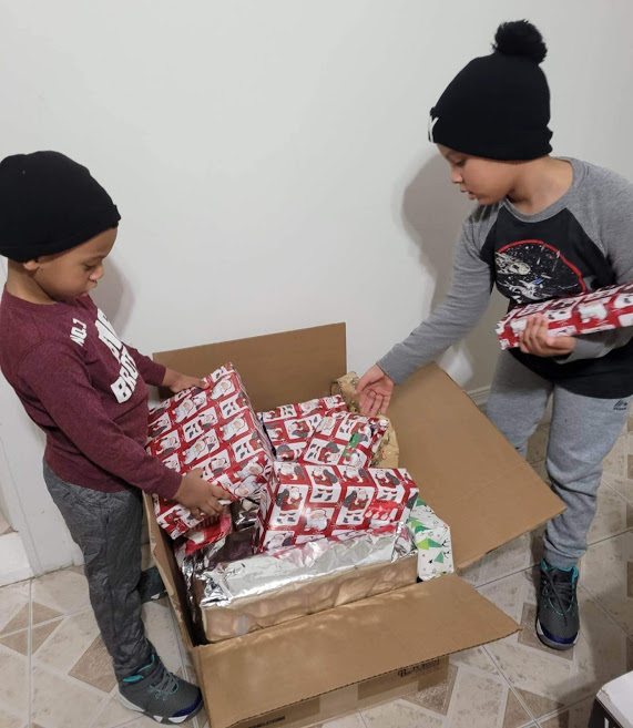Two boys putting gifts in a box full of gifts