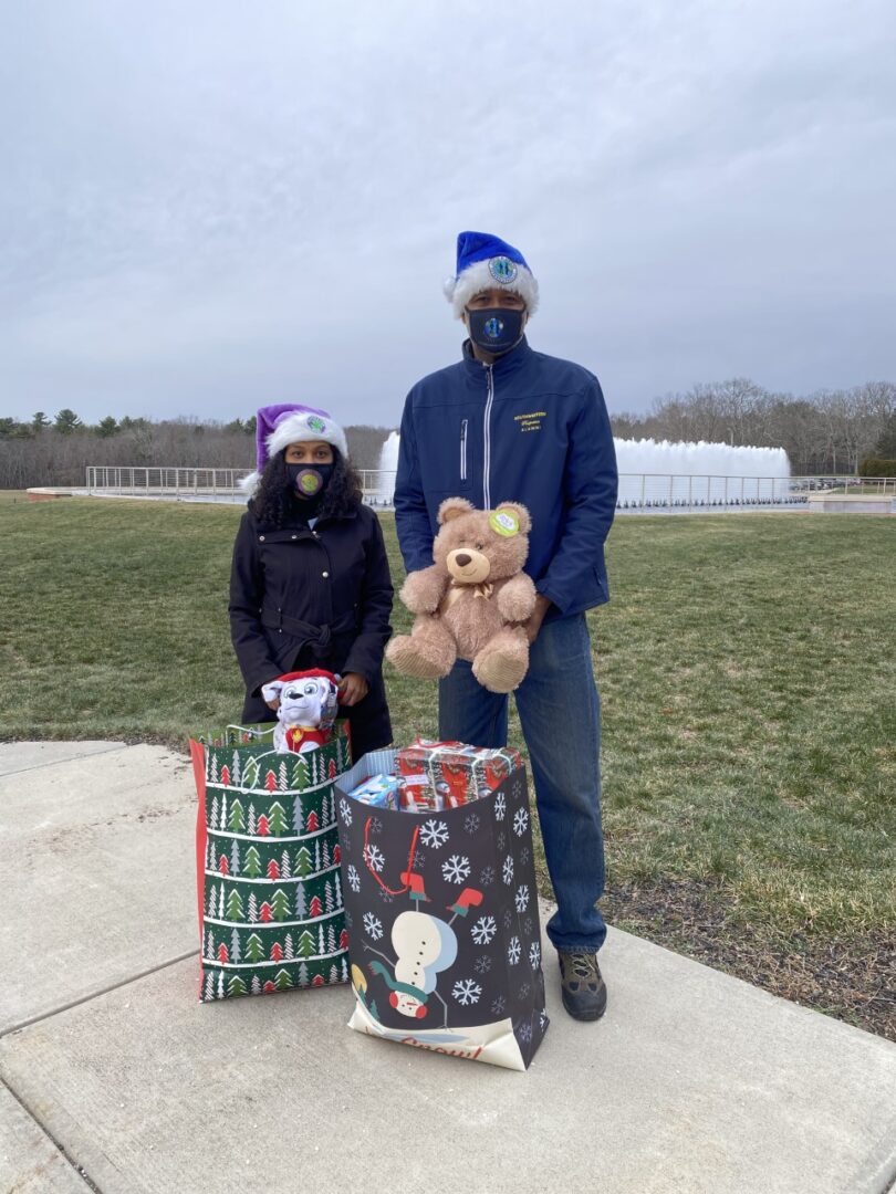 A woman and a man wearing masks and bringing bags of Christmas gifts