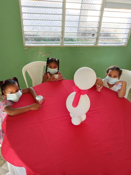 Three little girls in braids sitting at a table